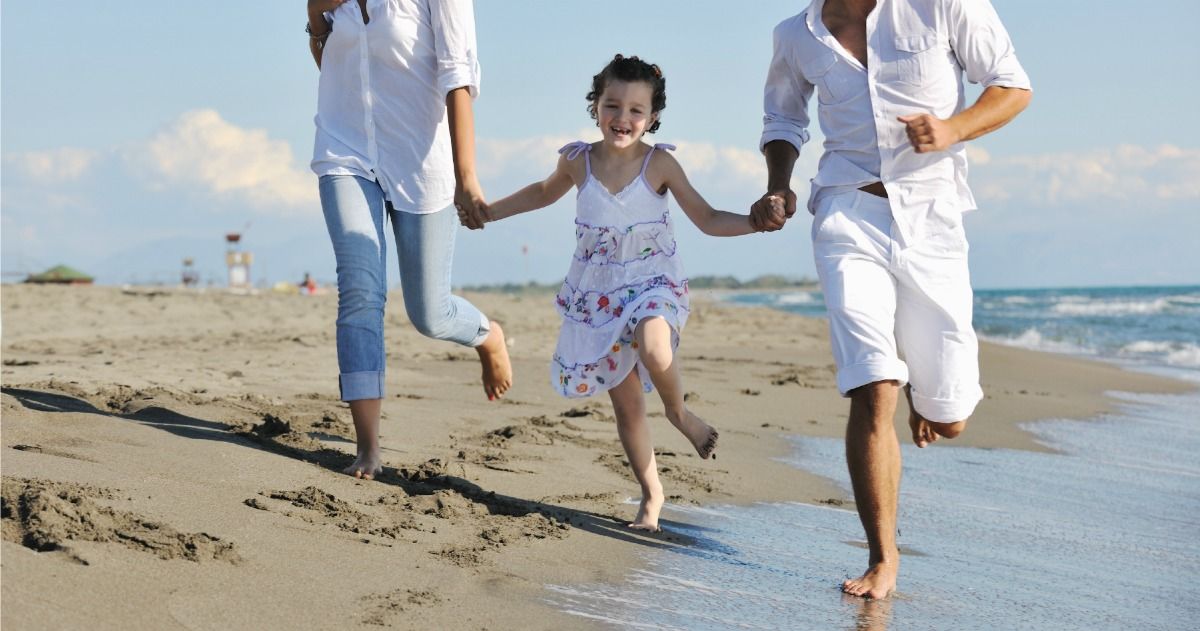 Parents walking on beach with child in middle holding their hands