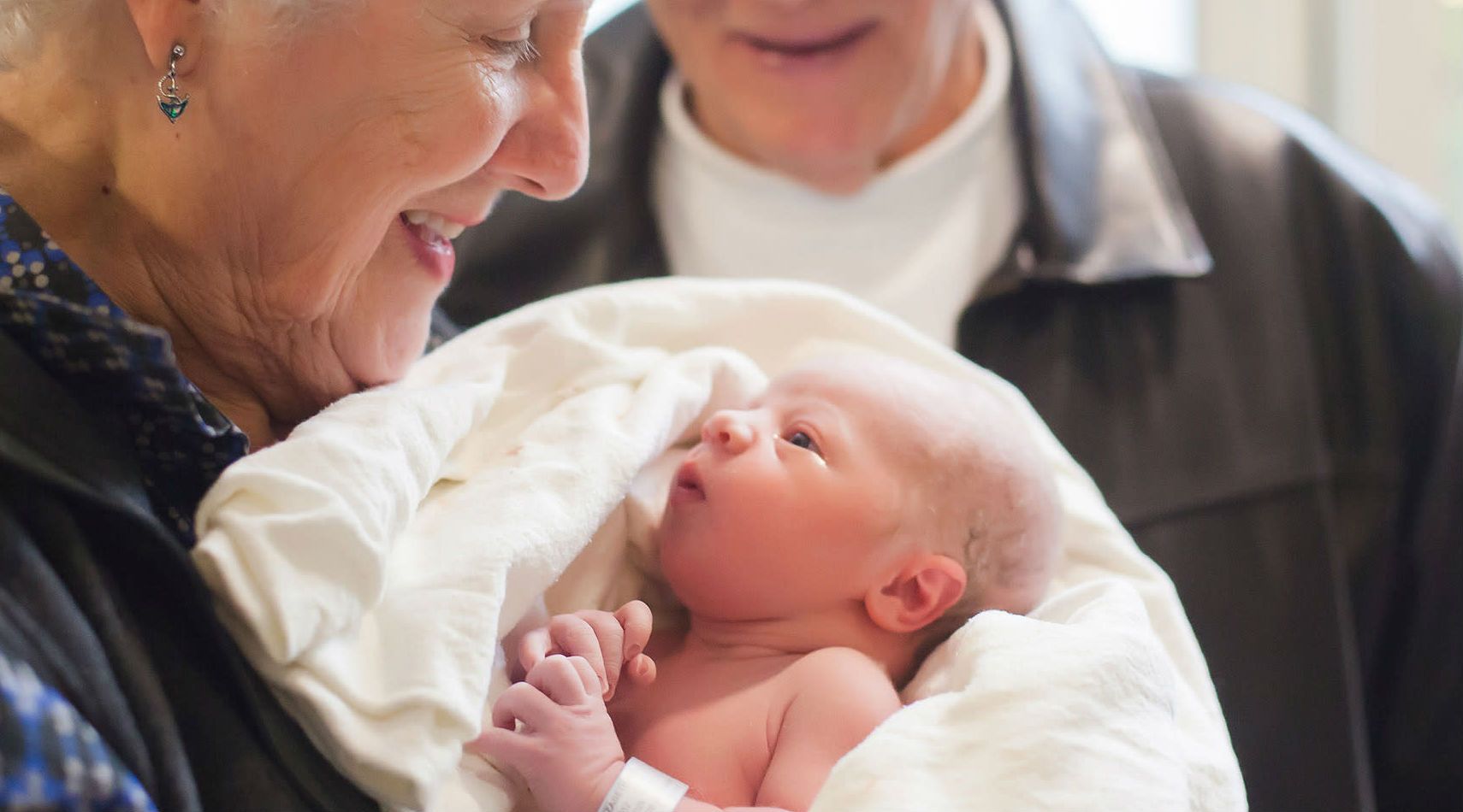 Picture of grandparents holding a newborn baby