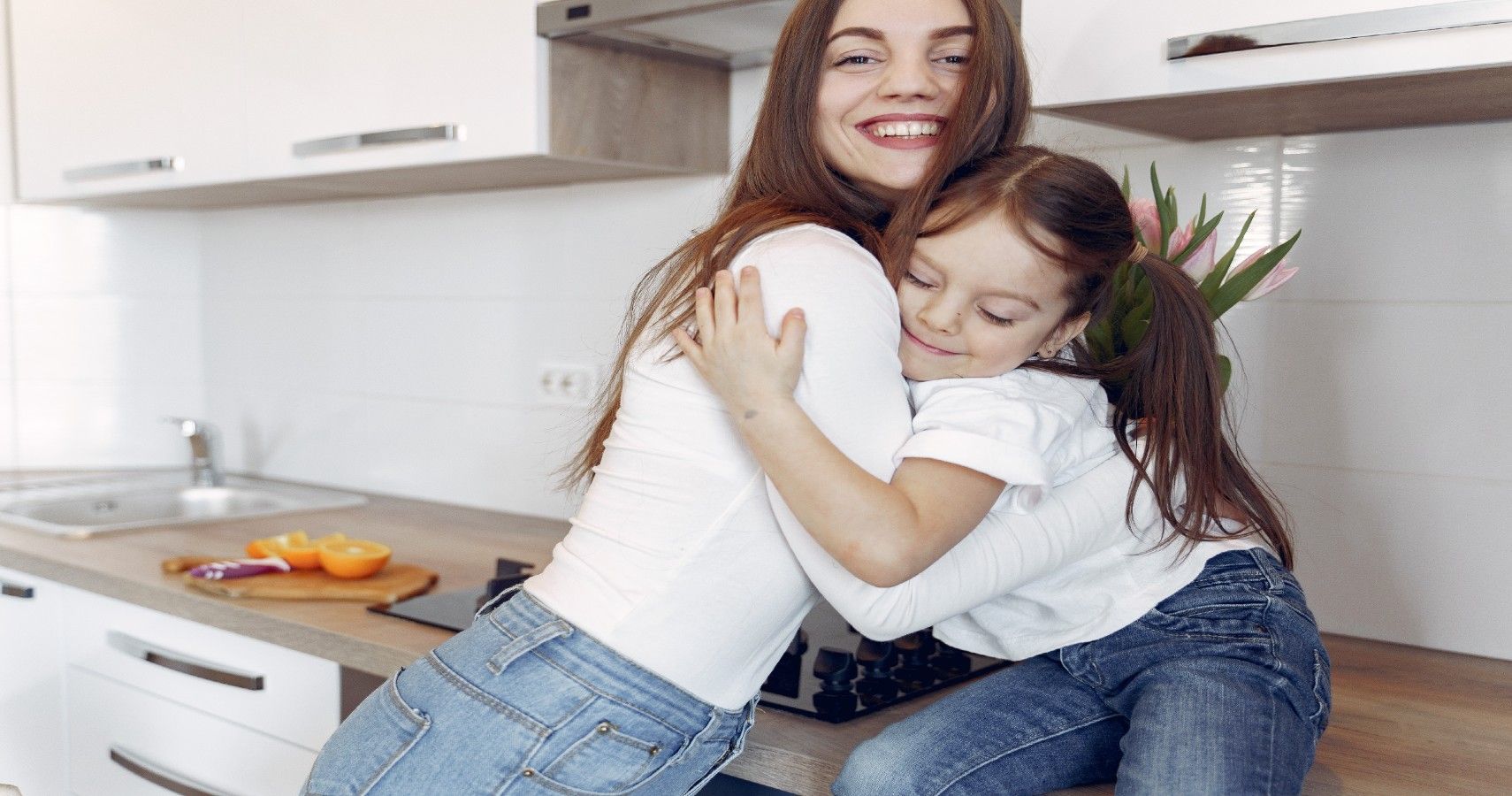 mother, daughter, hugging, blue jeans, white shirt, kitchen