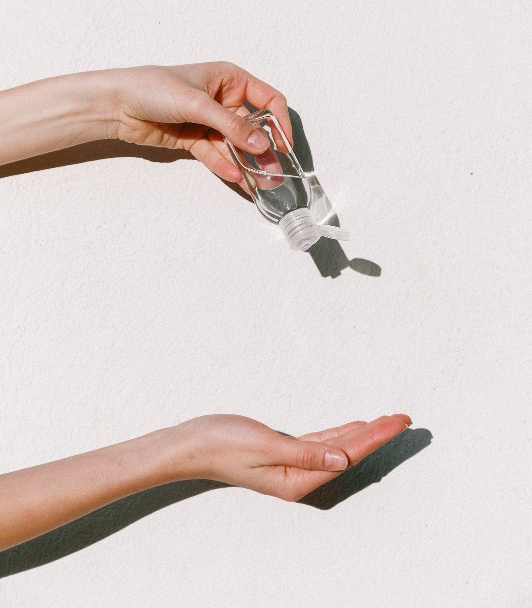Photo of hand underneath a bottle of hand sanitizer