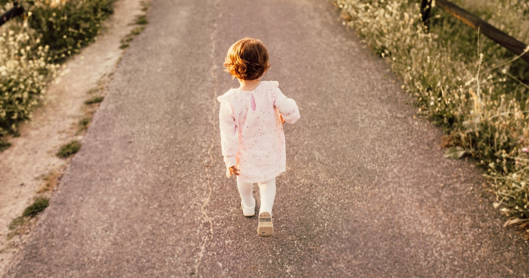 Toddler girl walking on paved road by herself