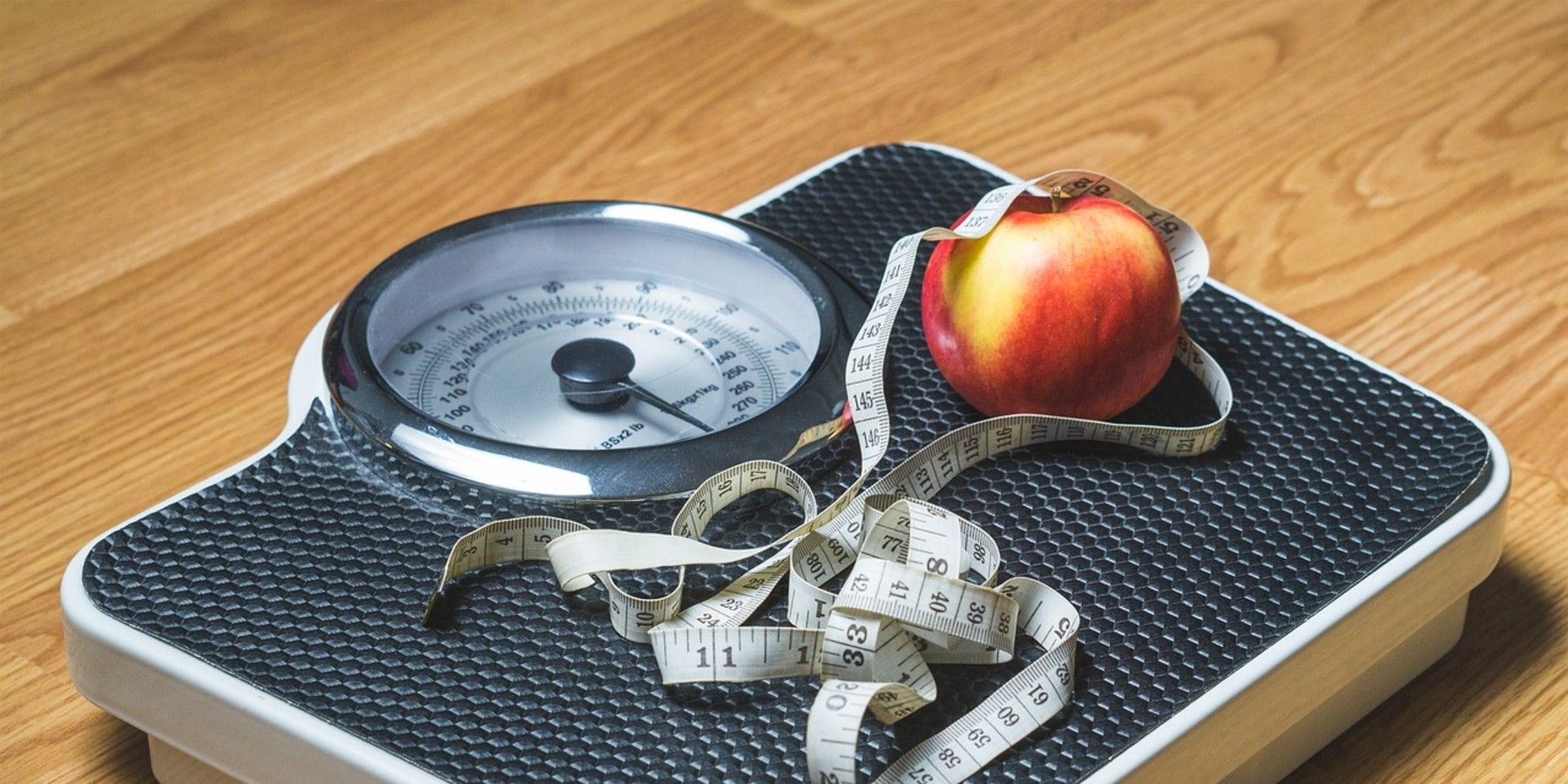 Scale with measuring tape and an apple, and the person who owns it might be losing weight.