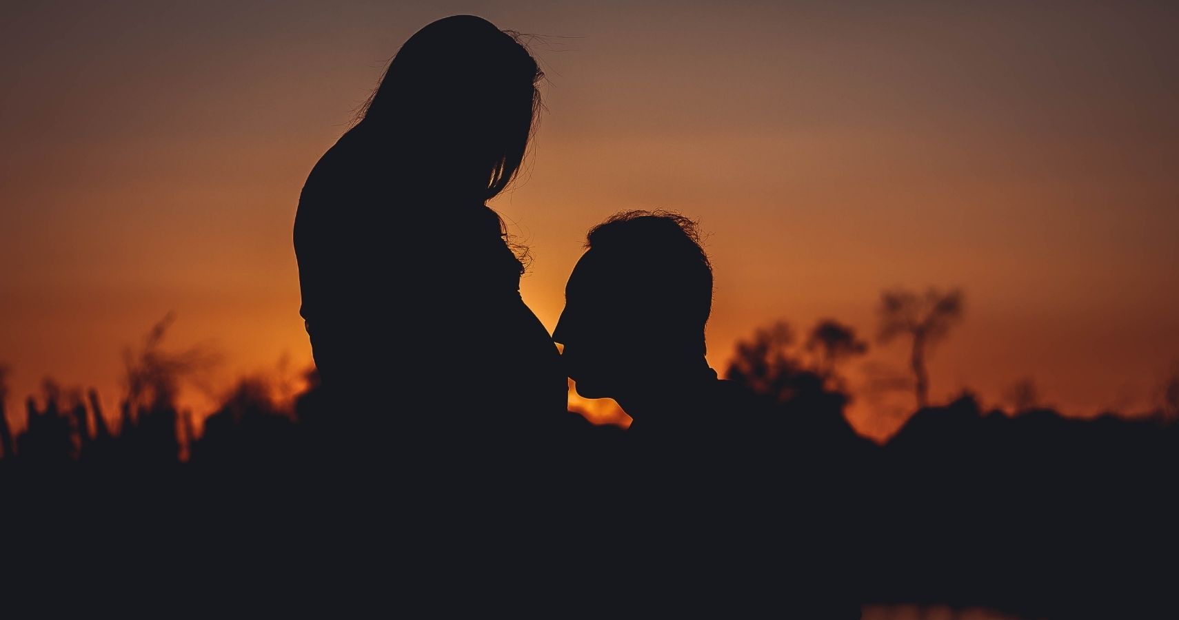 Man kissing baby bump silhouette