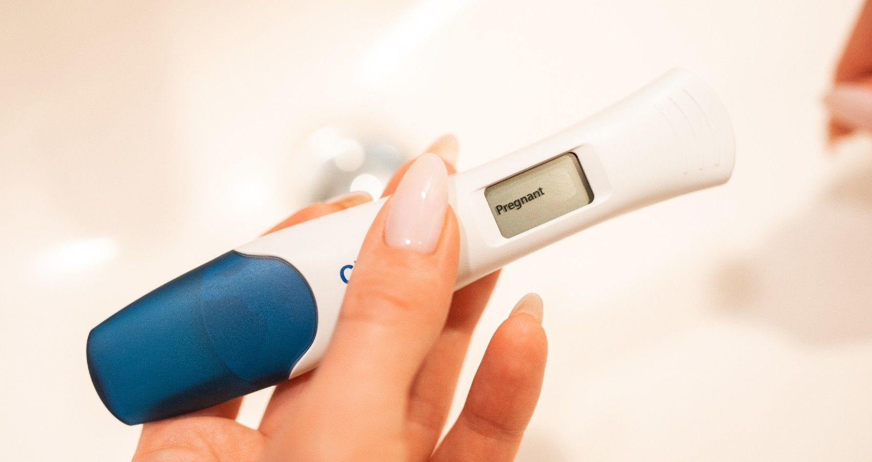 A woman's hand holding a positive pregnancy test