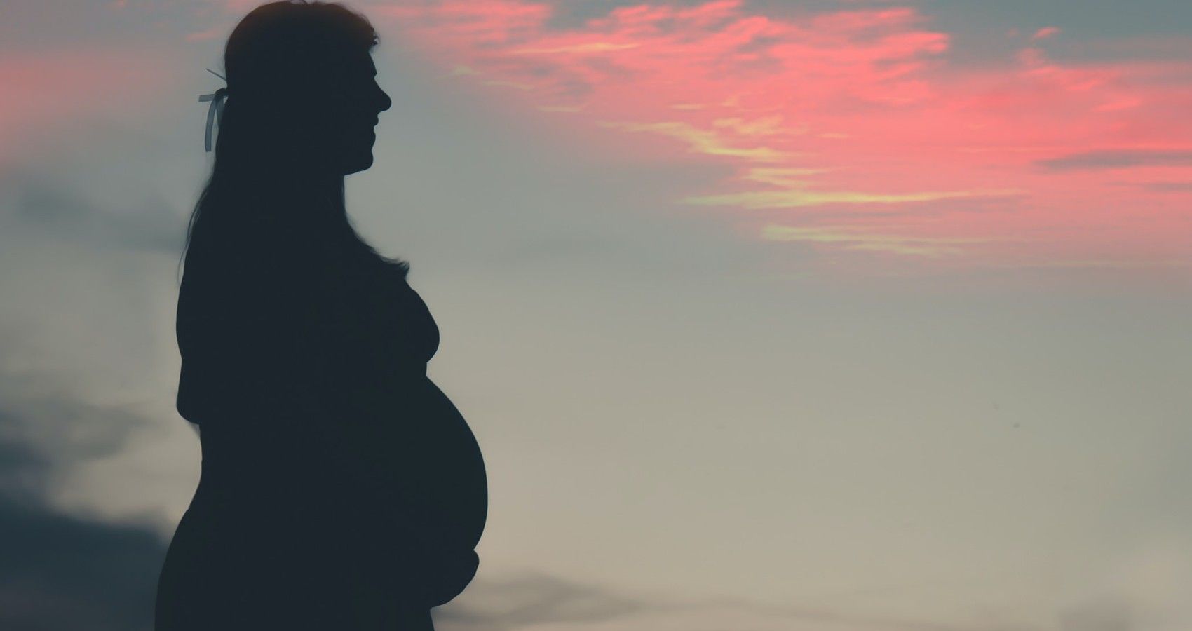 A-Pregnant-Woman-At-Dusk-Holding-Her-Bump-1