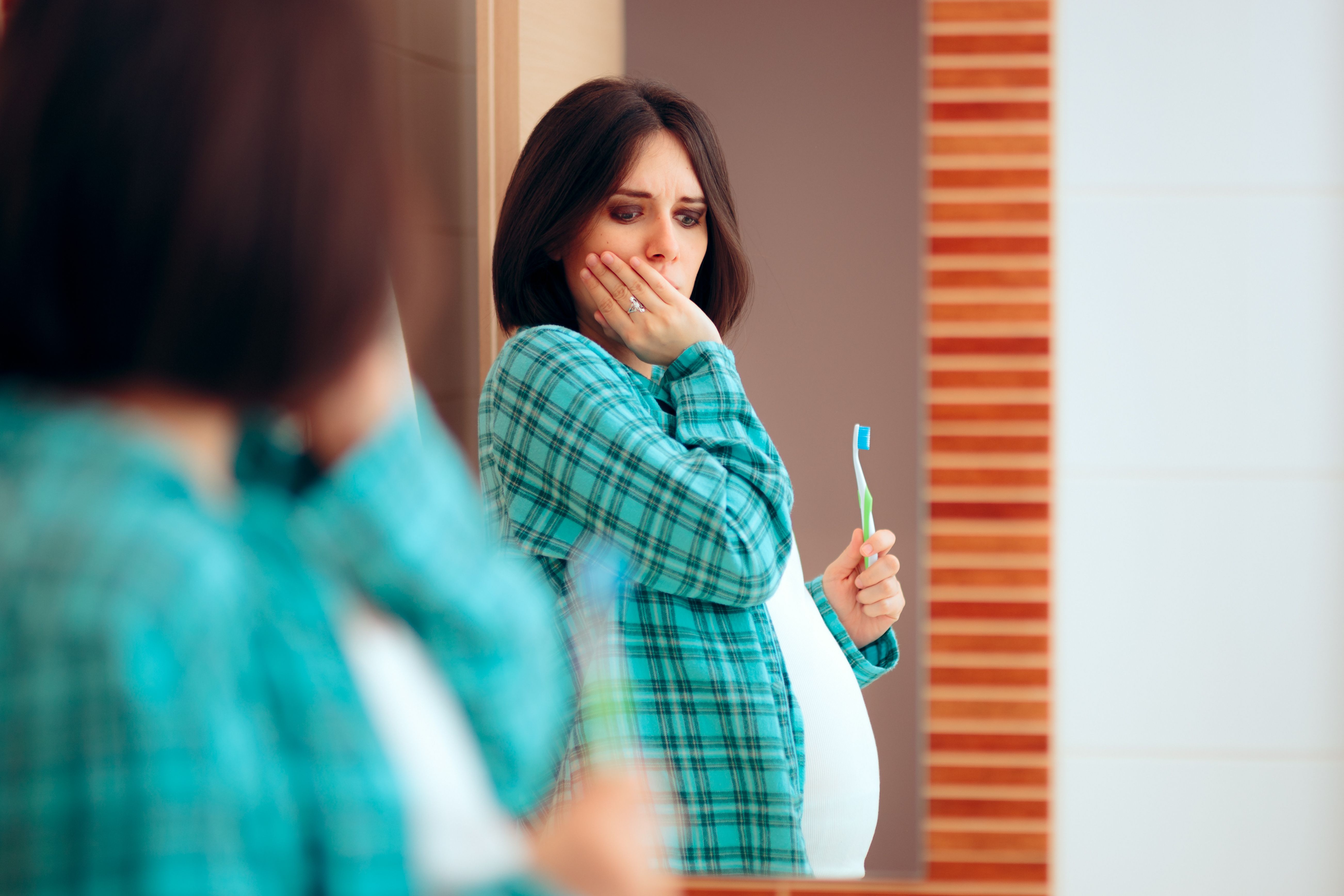 pregnant woman holding jaw and toothbrush