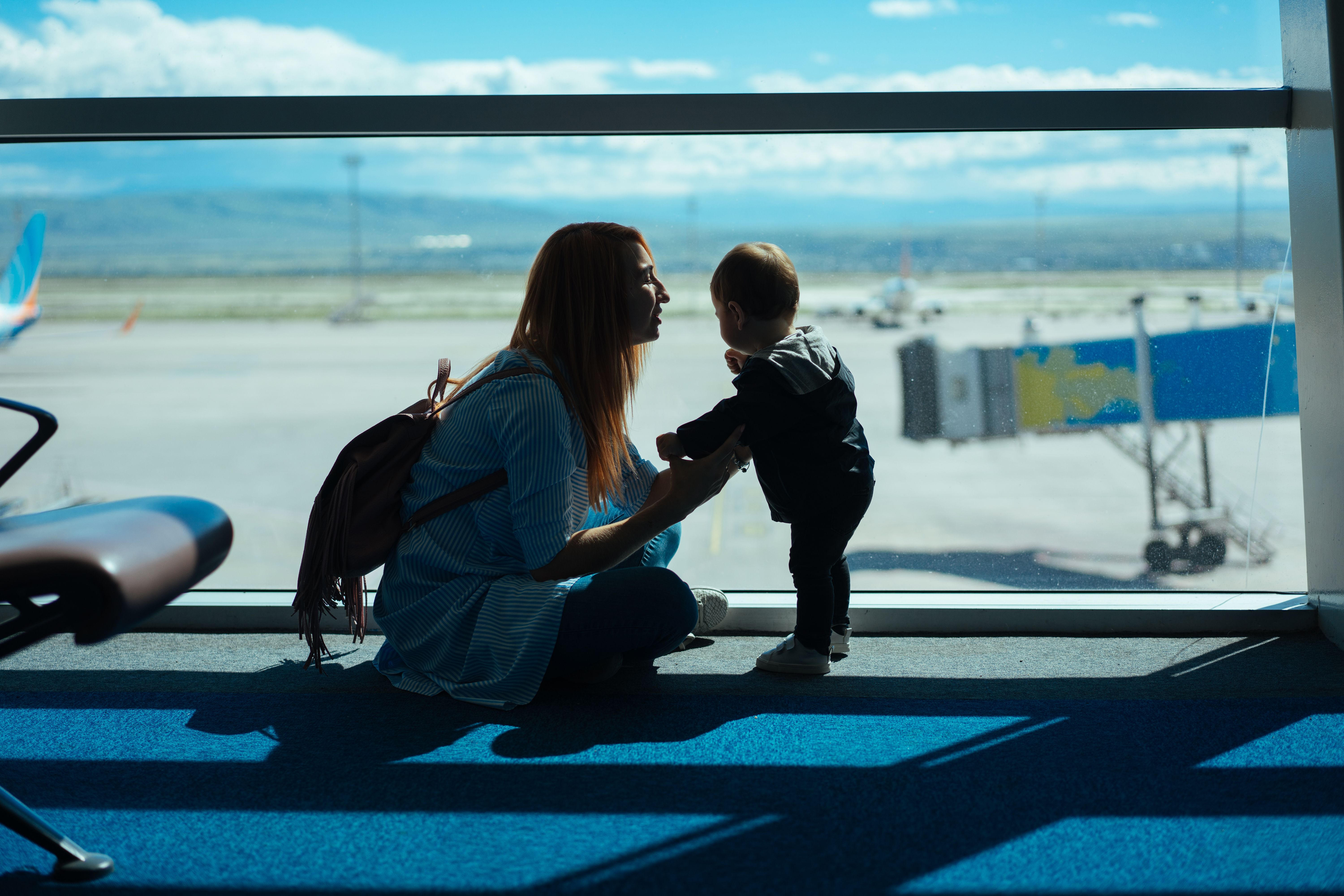 mom squatting down to toddler at airport
