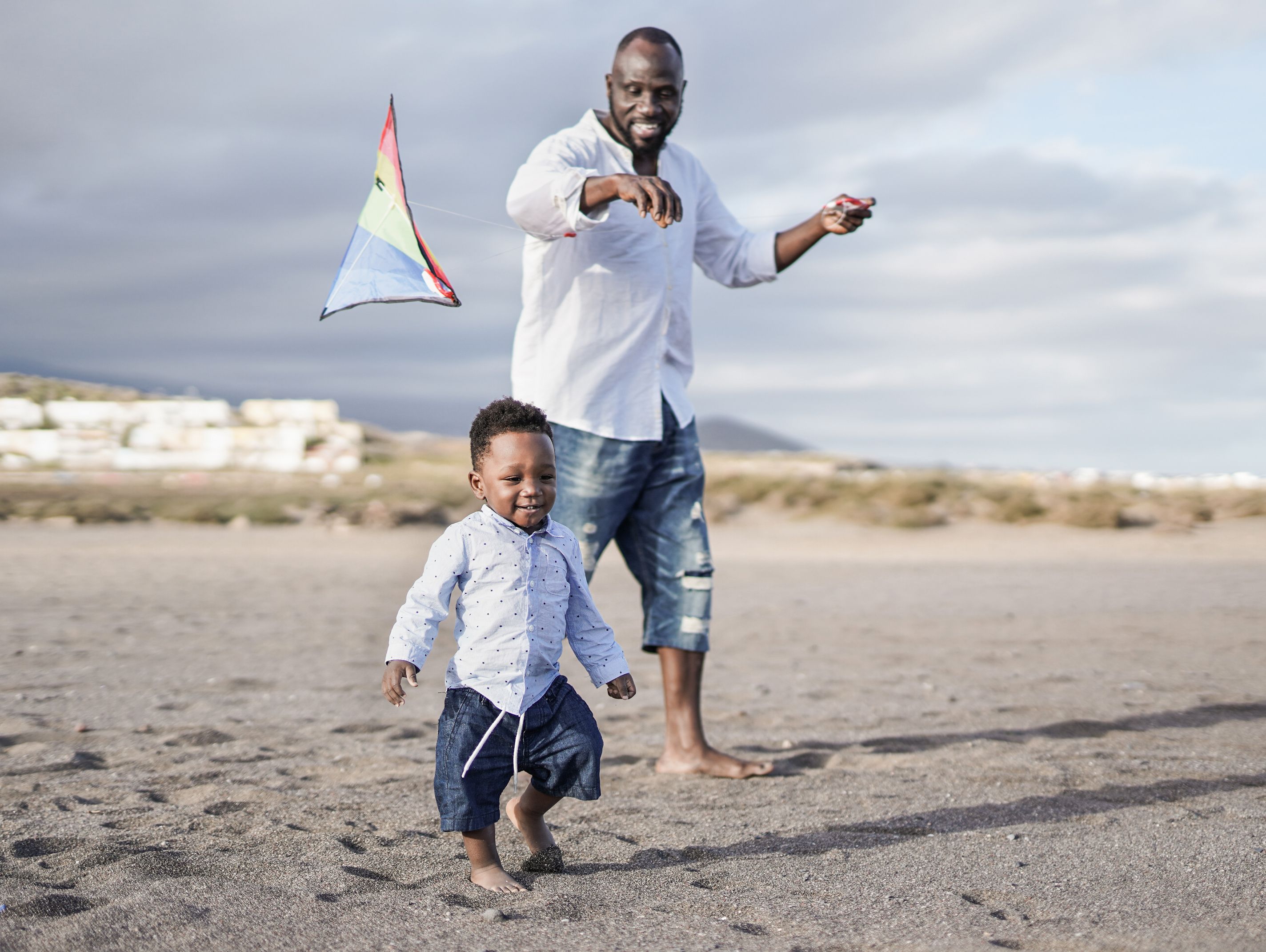 dad and toddler flying kite on the beach