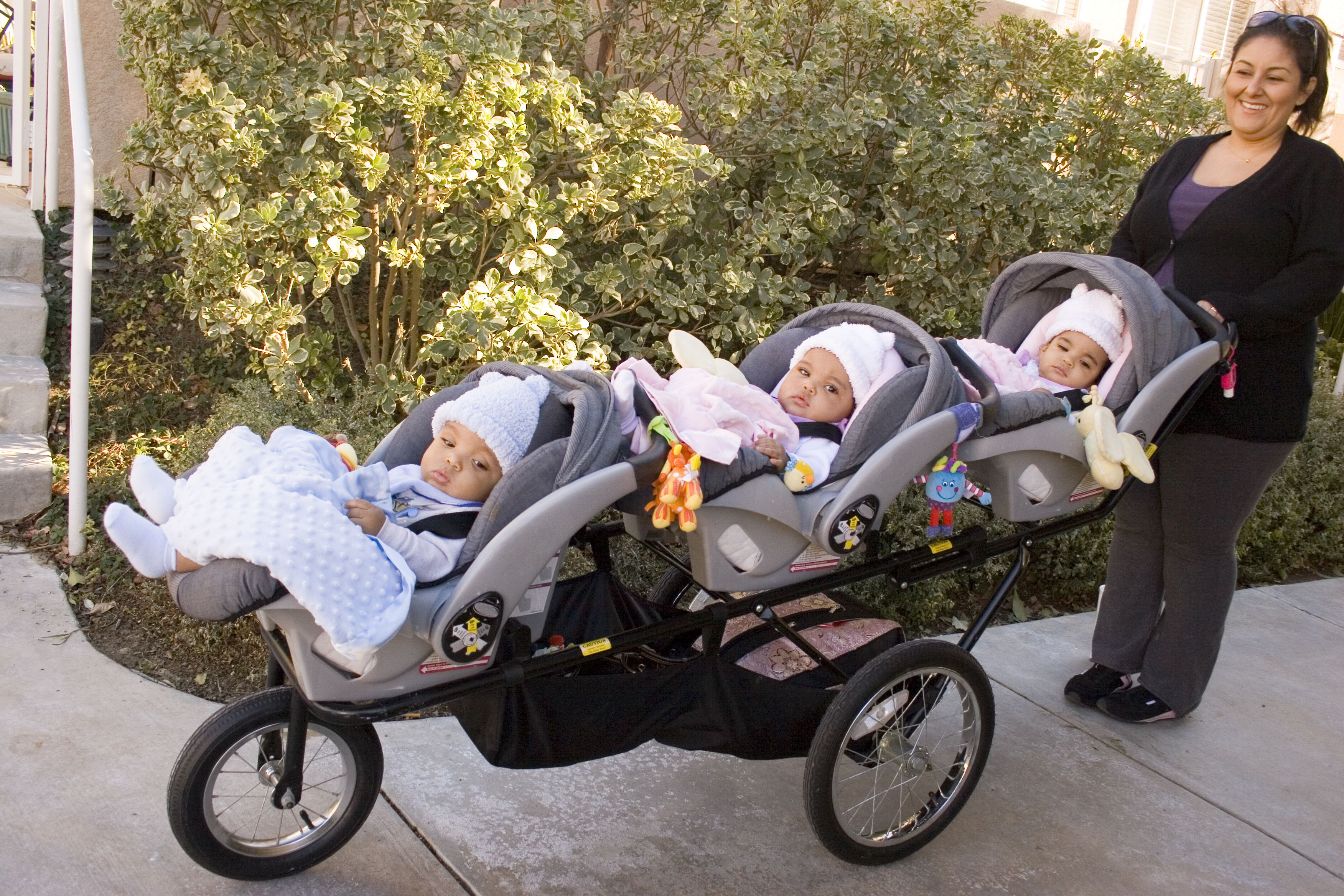 woman holding triplet stroller with baby car seats