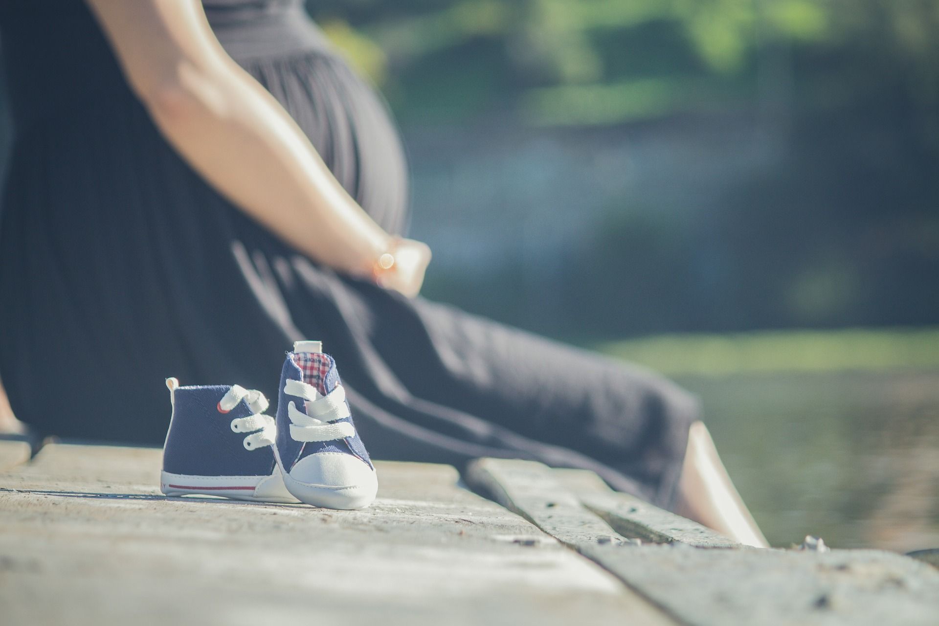 pregnant women sitting outside baby shoes