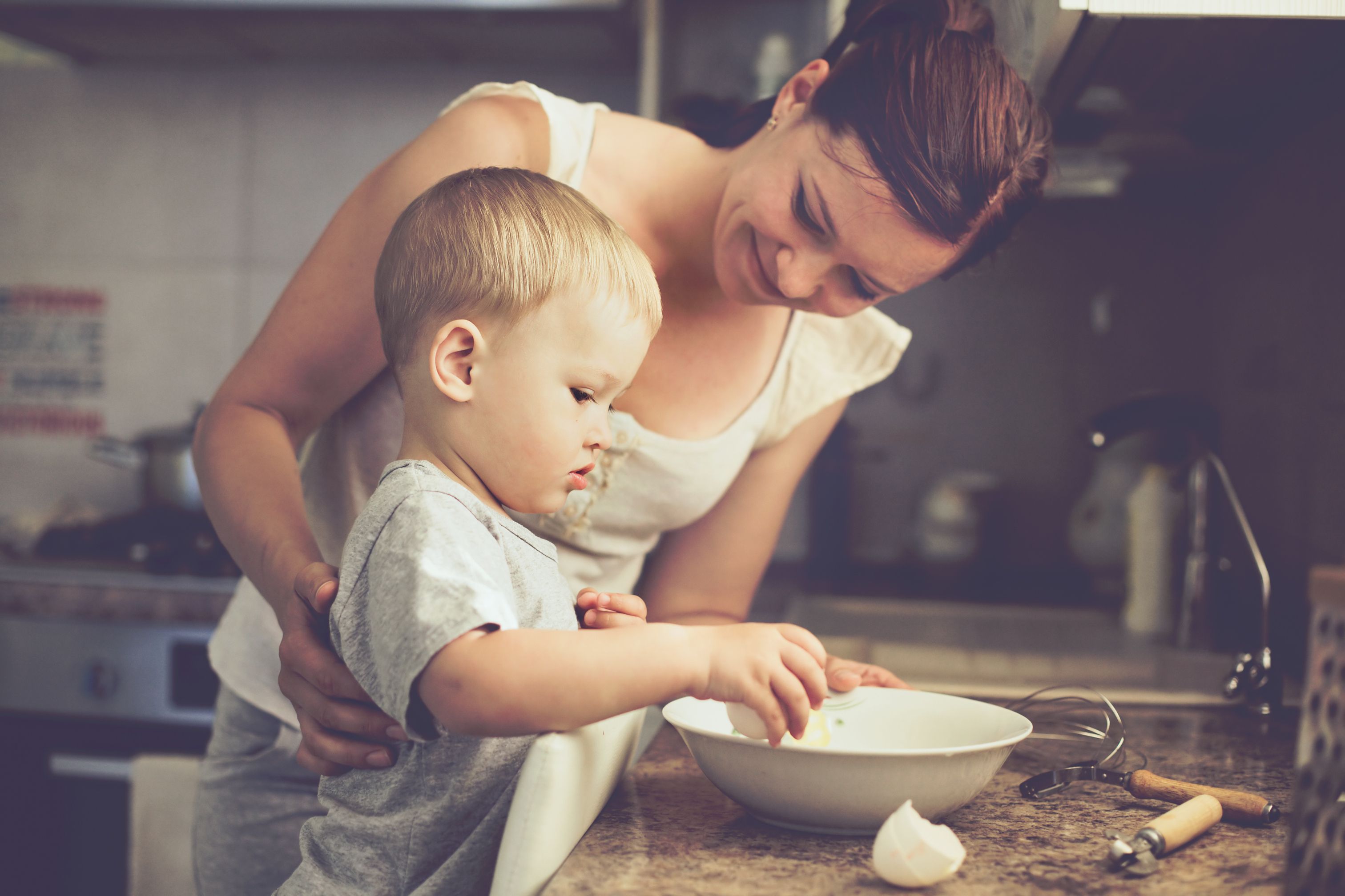 toddler boy baking with mom in kitchen