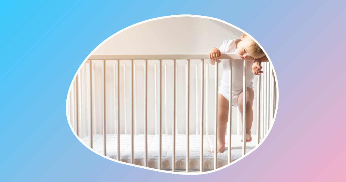 baby in a white outfit standing in a crib looking down
