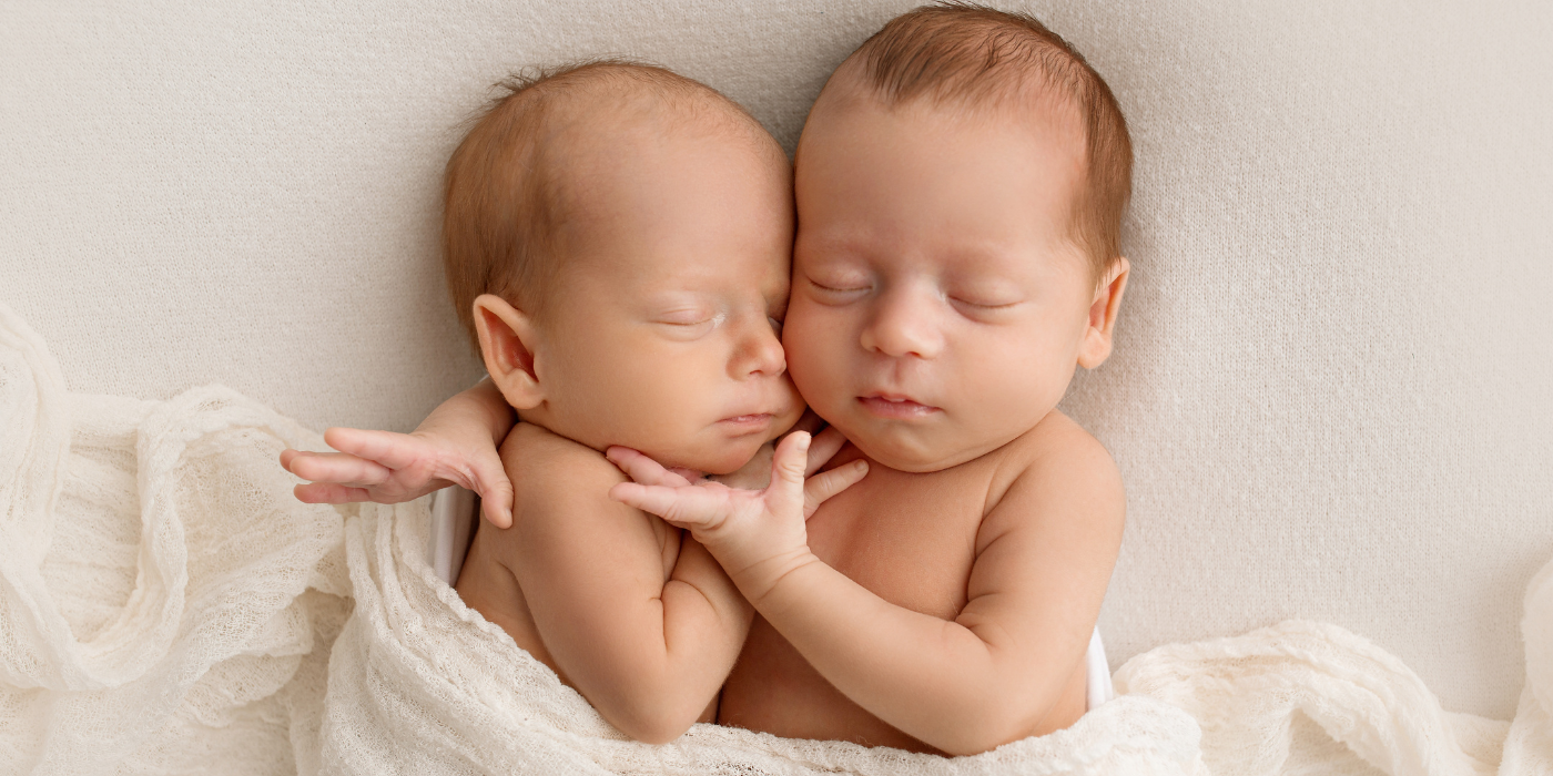 Newborn twins sleeping side by side 
